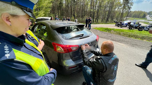 motocyklista naklejający na pojazd naklejkę