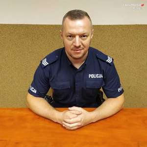 zdjęcie przedstawia policjanta siedzącego za biurkiem