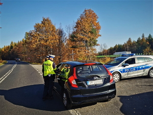 zdjęcie przedstawia policjantów stojących przy samochodzie kontrolujących trzeźwość kierującego