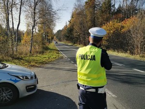 Zdjęcie przedstawia policjanta dokonującego pomiaru prędkości