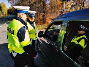 zdjęcie przedstawia policjantów stojących przy samochodzie kontrolujących trzeźwość kierującego