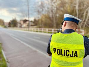 Na zdjęciu znajduję się policjant ruchu drogowego celujący radarem sprawdzającym prędkość samochodów.