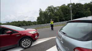 zdjęcie przedstawia policjanta zatrzymującego samochód do kontroli  drogowej