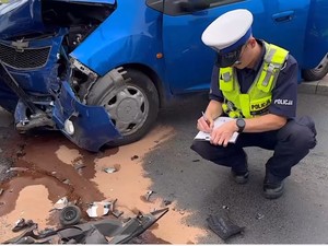 zdjęcie przedstawia policjanta dokonującego pomiarów na miejscu wypadku dorogowego