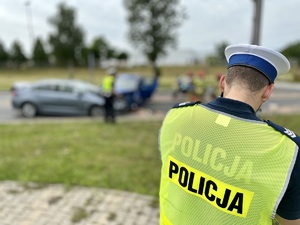 zdjęcie przedstawia policjanta dokonującego pomiarów na miejscu wypadku dorogowego