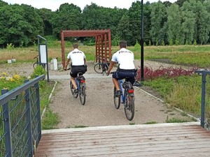 zdjęcie przedstawia policjantów na rowerach w trakcie patrolowania parku