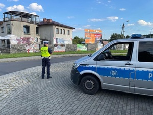 zdjęcie przedstawia policjanta w trakcie pomiaru prędkości samochodów