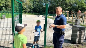 zdjęcie przedstawia policjanta rozdającego ulotki dzieciom na skateparku