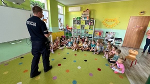 Zdjęcie przedstawia policjanta w trakcie pogadanki z dziećmi w przedszkolu