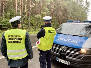 zdjęcie przedstawia policjanta i funkcjonariusza inspekcji transportu drogowego przy pojazdach