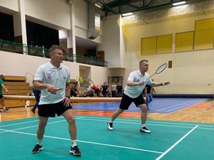 zdjęcie przedstawia zawodników w trakcie meczu badmintona na hali sportowej