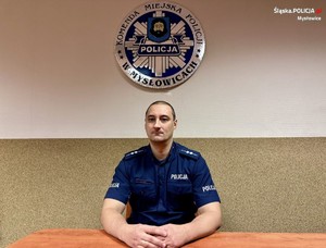 zdjęcie przedstawia policjanta siedzącego za biurkiem
