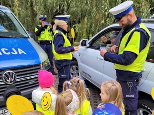 zdjęcie przedstawia dzieci wręczające kierowcy medalion uśmiechu w towarzystwie policjantki