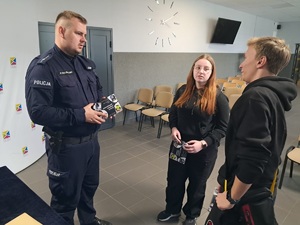 zdjęcie przedstawia policjanta w trakcie rozmowy z uczniami