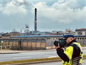 zdjęcie przedstawia policjanta wykonującego pomiar prędkości