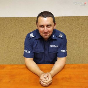 zdjęcie przedstawia policjanta siedzącego za biurkiem