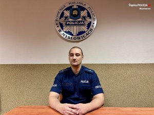 zdjęcie przedstawia policjanta siedzącego za biurkiem