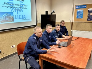 zdjęcie przedstawia policjantów siedzących przy biurku