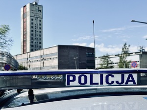 zdjęcie przedstawia napis policja na belce świetlnej radiowozu, w tle widać budynki kopalni