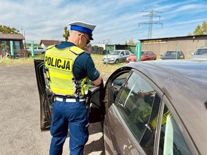 zdjęcie przedstawia policjanta w trakcie kontroli drogowej