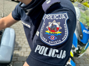 zdjęcie przedstawia naszywkę na mundurze policjanta z napisem Motocyklowa Asysta Honorowa Śląsk i wizerunkiem motocykla.