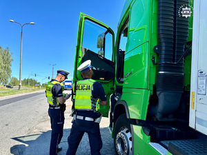 zdjęcie przedstawia policjantów w trakcie kontroli samochodu ciężarowego