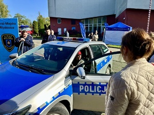 zdjęcie przedstawia policjantów w trakcie pikniku prezentujących radiowóz.