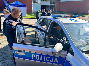 zdjęcie przedstawia policjantów w trakcie pikniku prezentujących radiowóz.