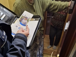 zdjęcie przedstawia policjanta przekazującego ulotki mieszkańcom