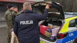 zdjęcie przedstawia policjanta doręczającego paczkę do potrzebujących rodzin