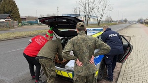 zdjęcie przedstawia policjanta doręczającego paczkę do potrzebujących rodzin