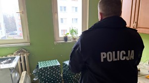 zdjęcie przedstawia policjanta doręczającego paczkę do potrzebujących rodzin