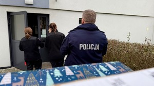 zdjęcie przedstawia policjanta doręczającego paczkę do potrzebujących rodzin