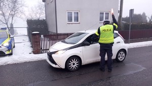 zdjęcie przedstawia policjanta w trakcie kontroli trzeźwości kierującego