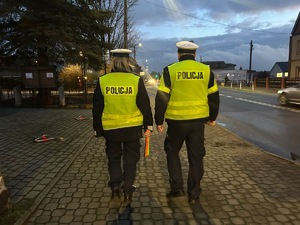 zdjęcie przedstawia policjantów rozdających odblaski przechodniom