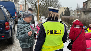 zdjęcie przedstawia dziecko wraz z policjantką wręczające serduszko seniorowi