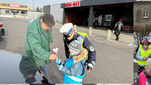 zdjęcie przedstawia dziecko wraz z policjantką wręczające serduszko seniorowi