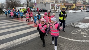 zdjęcie przedstawia dziecko wraz z policjantką wręczające serduszko seniorowi