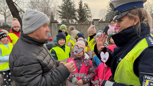 zdjęcie przedstawia dziecko wraz z policjantką wręczające serduszko seniorowi