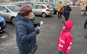 zdjęcie przedstawia dziecko wraz z policjantką wręczające serduszko seniorowi