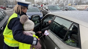 zdjęcie przedstawia dziecko wraz z policjantką wręczające serduszko seniorowi