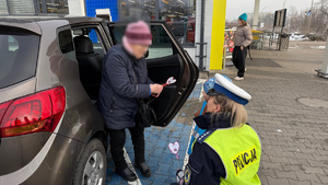 zdjęcie przedstawia dziecko wraz z policjantką wręczające serduszko seniorowi