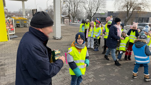 zdjęcie przedstawia dziecko wraz z policjantką wręczające serduszko seniorowi