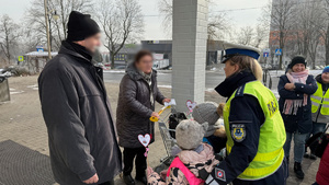 zdjęcie przedstawia dziecko wraz z policjantką wręczające serduszko seniorowi