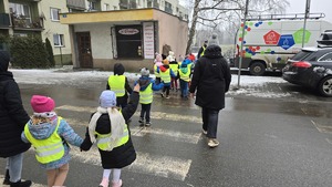 zdjęcie przedstawia policjantkę i dzieci w trakcie rozdawania serduszek uczestnikom ruchu drogowego