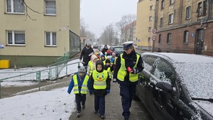 zdjęcie przedstawia policjantkę i dzieci w trakcie rozdawania serduszek uczestnikom ruchu drogowego