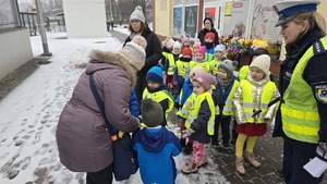 zdjęcie przedstawia policjantkę i dzieci w trakcie rozdawania serduszek uczestnikom ruchu drogowego