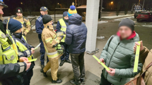 zdjęcie przedstawia policjantów, strażaków i strażników miejskich rozdających odblaski przechodniom