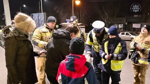 zdjęcie przedstawia policjantów, strażaków i strażników miejskich rozdających odblaski przechodniom