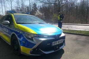 zdjęcie przedstawia policjanta wykonującego pomiar prędkości